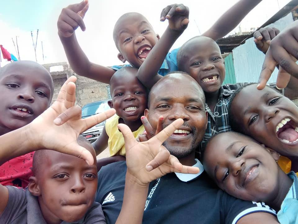 Danny Kioko smiling with children supported by DKF